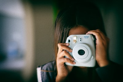使用白色富士胶片Instax Mini拍照的女性